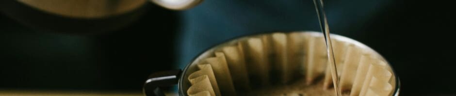 Close-up of a manual pour over coffee brewing process, highlighting the coffee and filter.